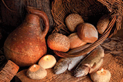 Two fish and five loaves of bread with candle-light and an antique wine jar