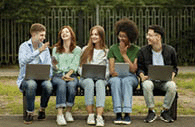 Group of college students with laptops and tablet studying outdoors