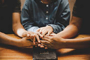 Family praying together with parent at home