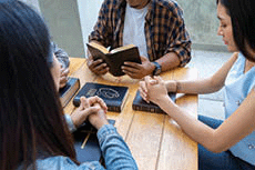 Group of people clasping hands praying.