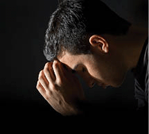 Young man praying earnestly in the dark.